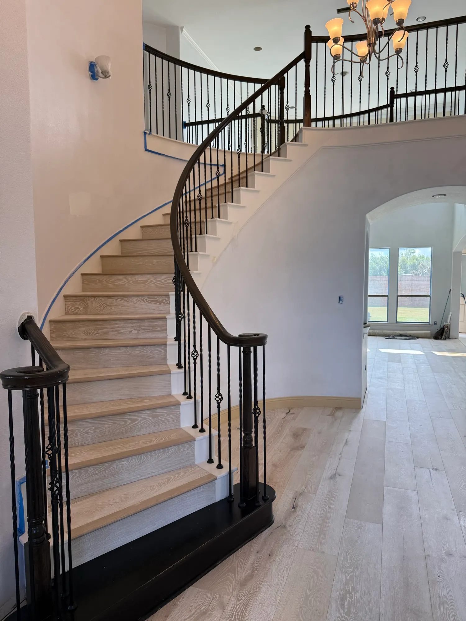 After: light oak stair treads, black risers and matching wide-plank floors on a curved staircase