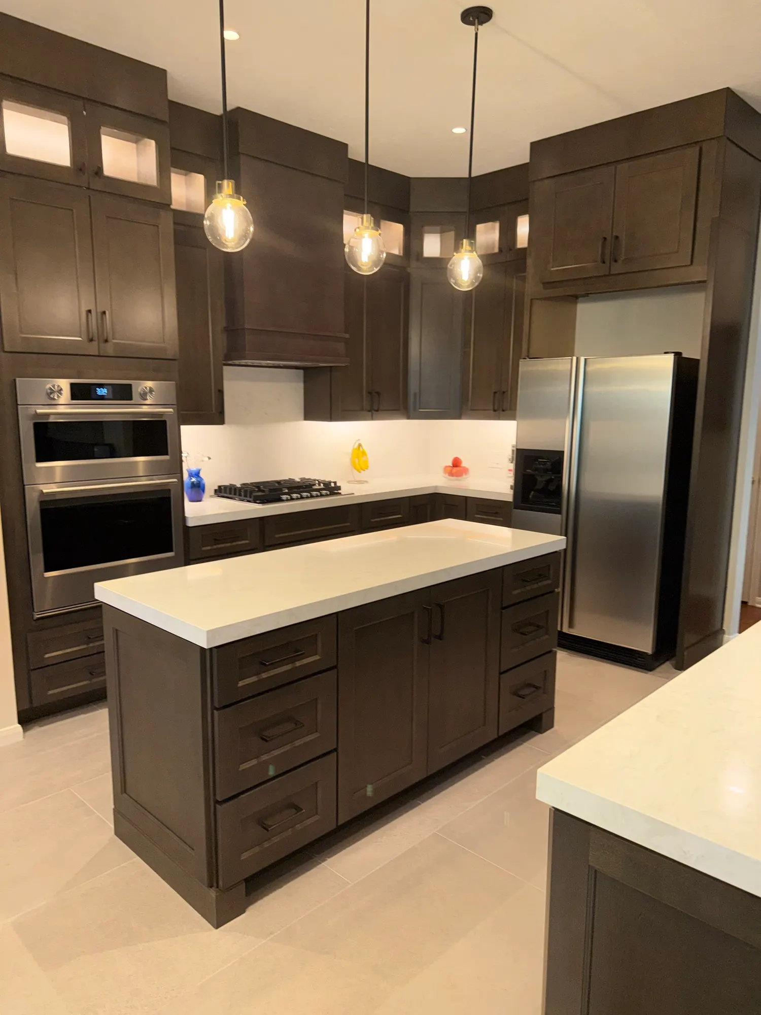 After: espresso shaker cabinets to the ceiling, white quartz island, glass pendants and porcelain tile floors