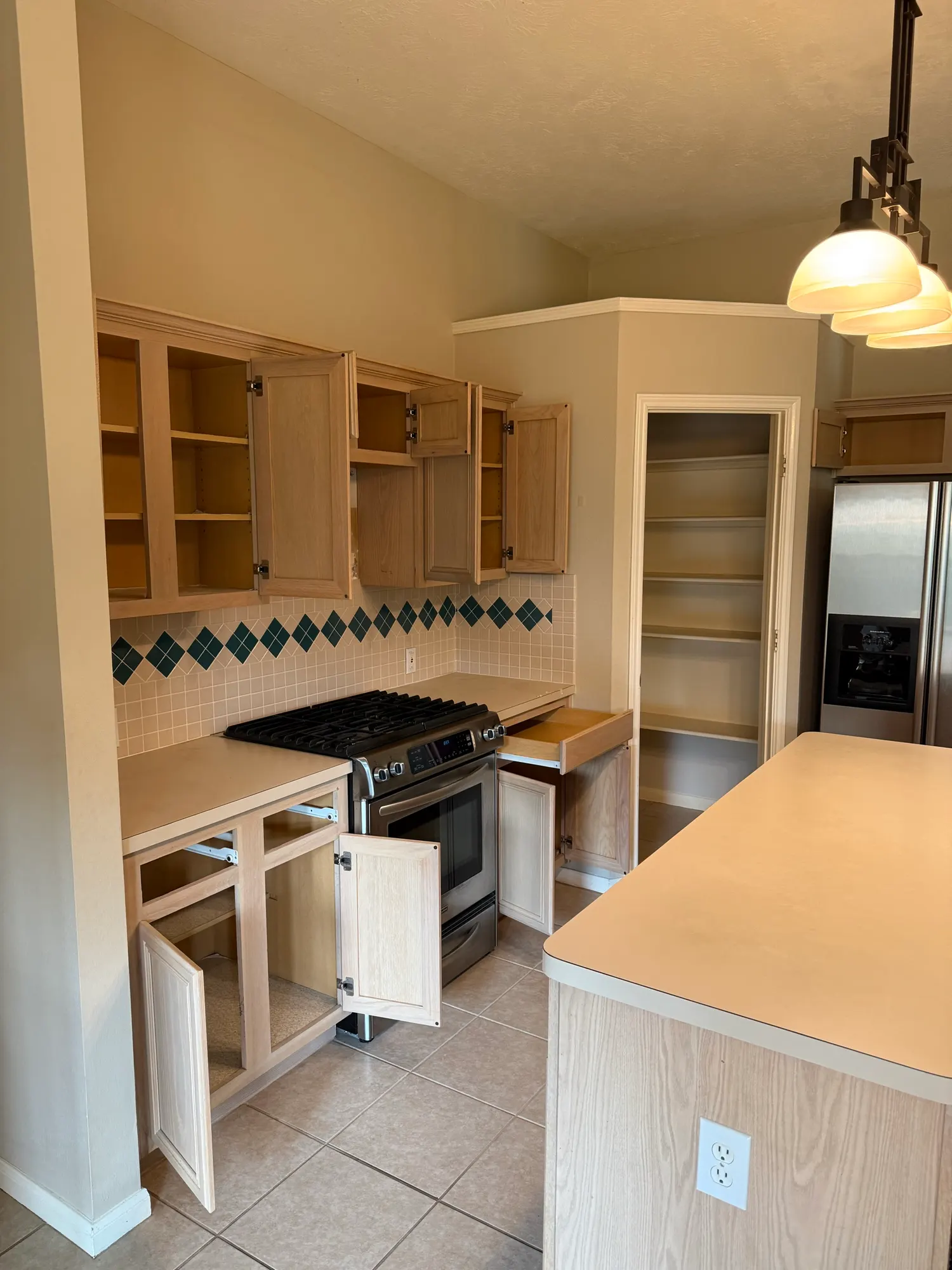 Before: oak cabinets and laminate countertops beside a gas range